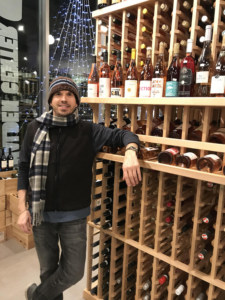 Picture of Dante Fiorenza standing next to rack of wine bottles