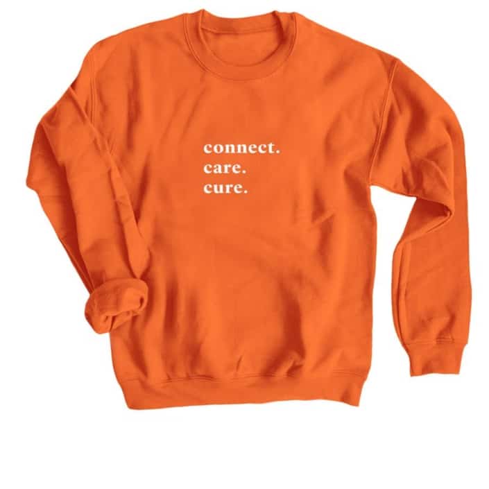 Orange crewneck sweatshirt with words "Connect. Care. Cure." in white text.