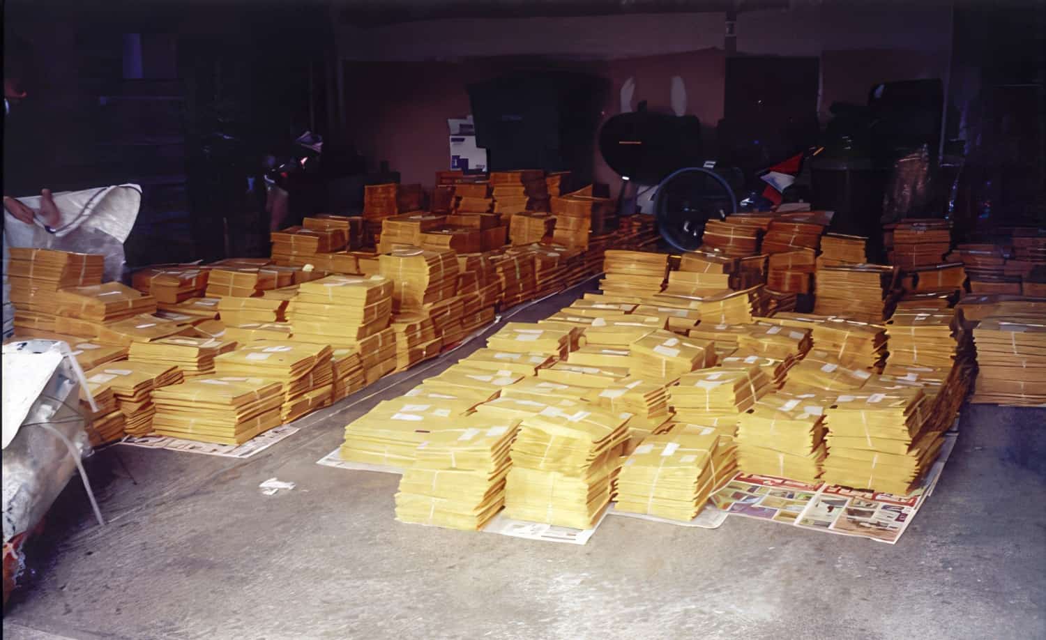 Stacks of envelopes bundled and organized on a garage floor for The Transverse Myelitis Association international mailing in 2002.